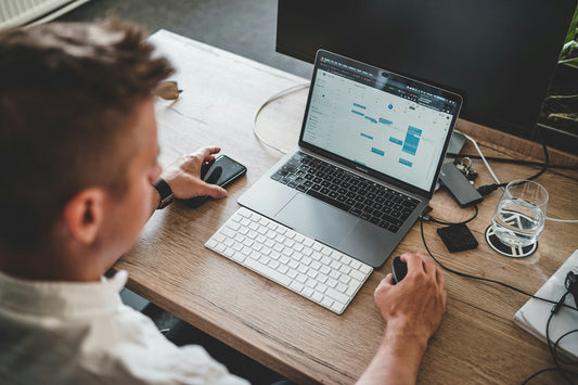 Homme travaillant à son bureau sur ordinateur avec clavier et souris sans fil ergonomiques, setup moderne et confortable pour télétravail.
